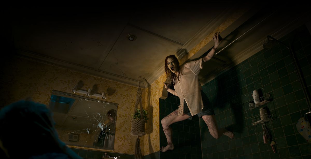 Nybesatt Deadite Ellie (Alyssa Sutherland) väser genom en svärtad mun medan hon klamrar sig fast vid en vägg i sin mörka lägenhet i Evil Dead Rise