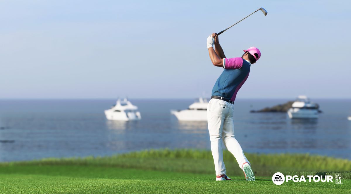En golfare i blå skjorta och vita byxor svingar ett strykjärn på Pebble Beach fairway, med tre yachter i fjärran utanför Montereys kustlinje, i EA Sports PGA Tour