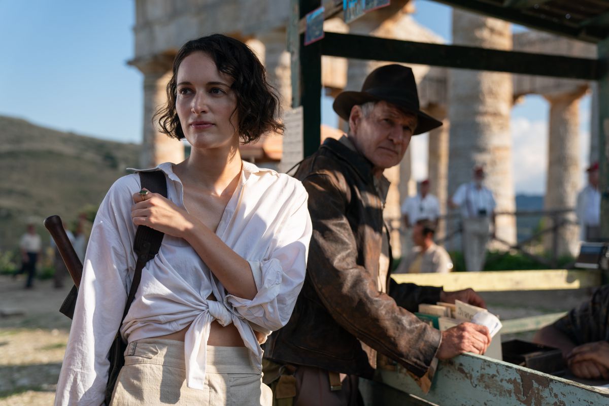 Phoebe Waller-Bridge wears white next to Harrison Ford as Indiana Jones, wearing his classic Indiana Jones outfit, in Dial of Destiny.