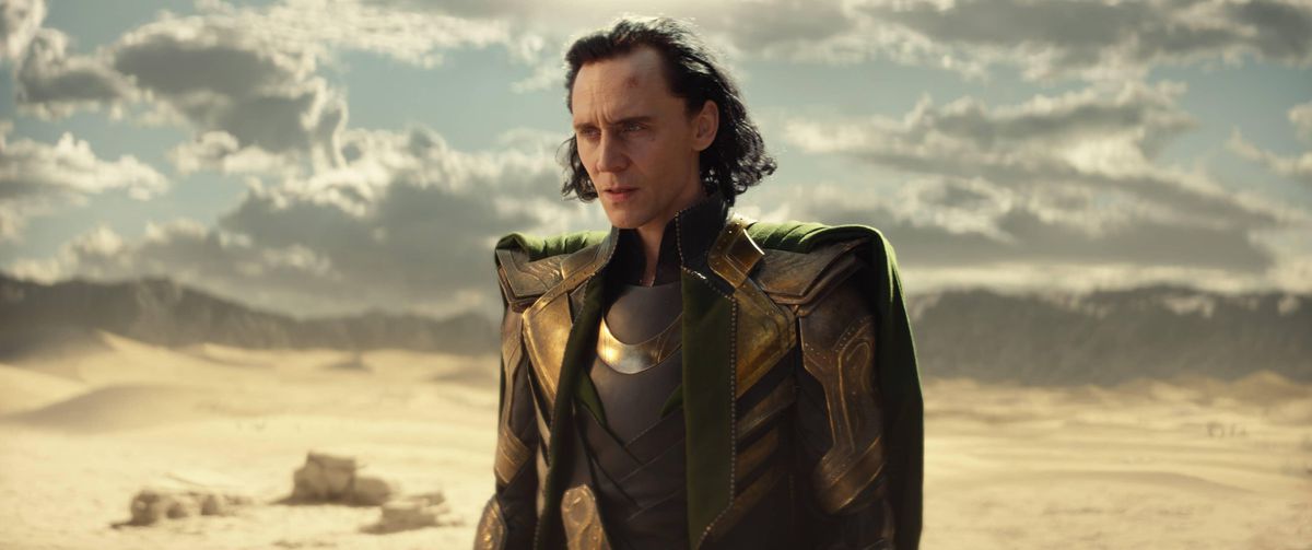 Loki (Tom Hiddleston) stands in a desert in a scene from the first season of Loki