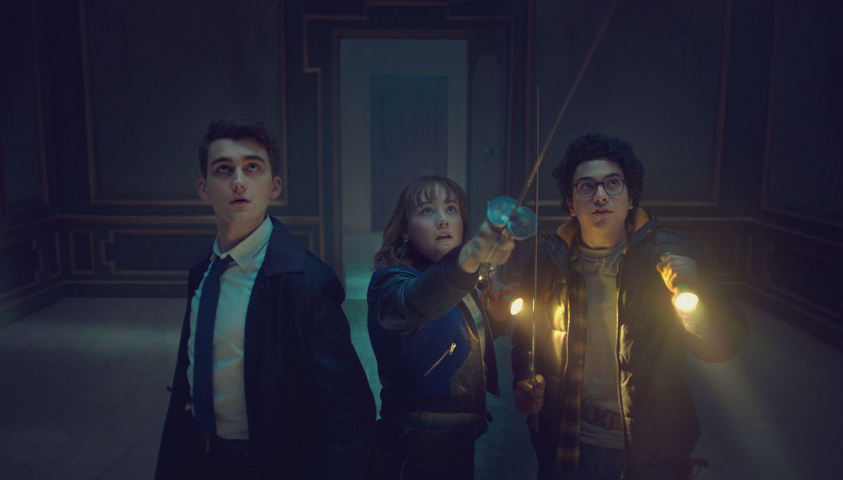 A group of children hold swords and flashlights in a dark room in Lockwood and Co.