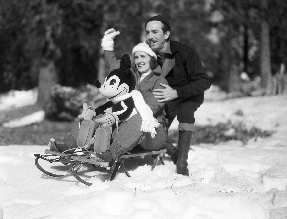 I ett odaterat svartvitt porträtt hukar Walk Disney bakom sin fru Lillian och en Musse Pigg-docka, båda sittande på en gammaldags träsläde med metalllöpare, utomhus i snön