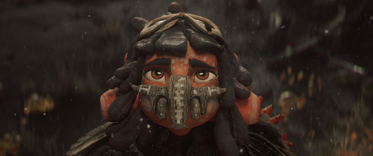 A young orange-skinned alien girl, wearing a protective mask made of stone and wood. She looks up at the camera, brown eyes wide with worry.