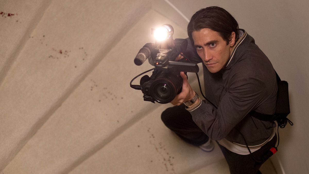 Jake Gyllenhaal as Louis “Lou” Bloom pointed a camera upward a flight of stairs in Nightcrawler.