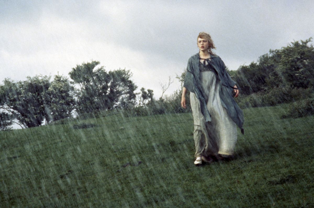 Kate Winslet walks through heavy rain on a heath, dressed in Regency attire