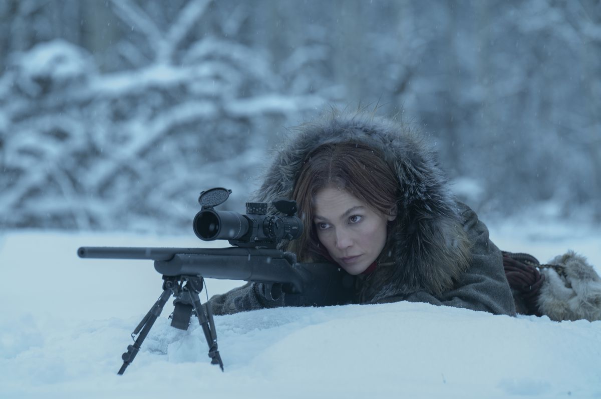 Jennifer Lopez lägger sig med ett prickskyttegevär i snön, med en tung päls på, i The Mother.