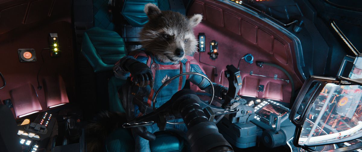 Den antropomorfiska tvättbjörnen Rocket (kroppsspelad av Sean Penn, röstad av Bradley Cooper) sitter i sittbrunnen på ett rymdskepp i komplett Guardians of the Galaxy blå-och-röd jumpsuit-uniform i Guardians of the Galaxy Vol.  3