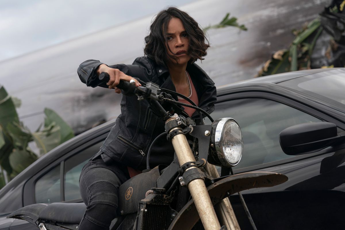 Letty (Michelle Rodriguez) på en motorcykel framför en bil i F9