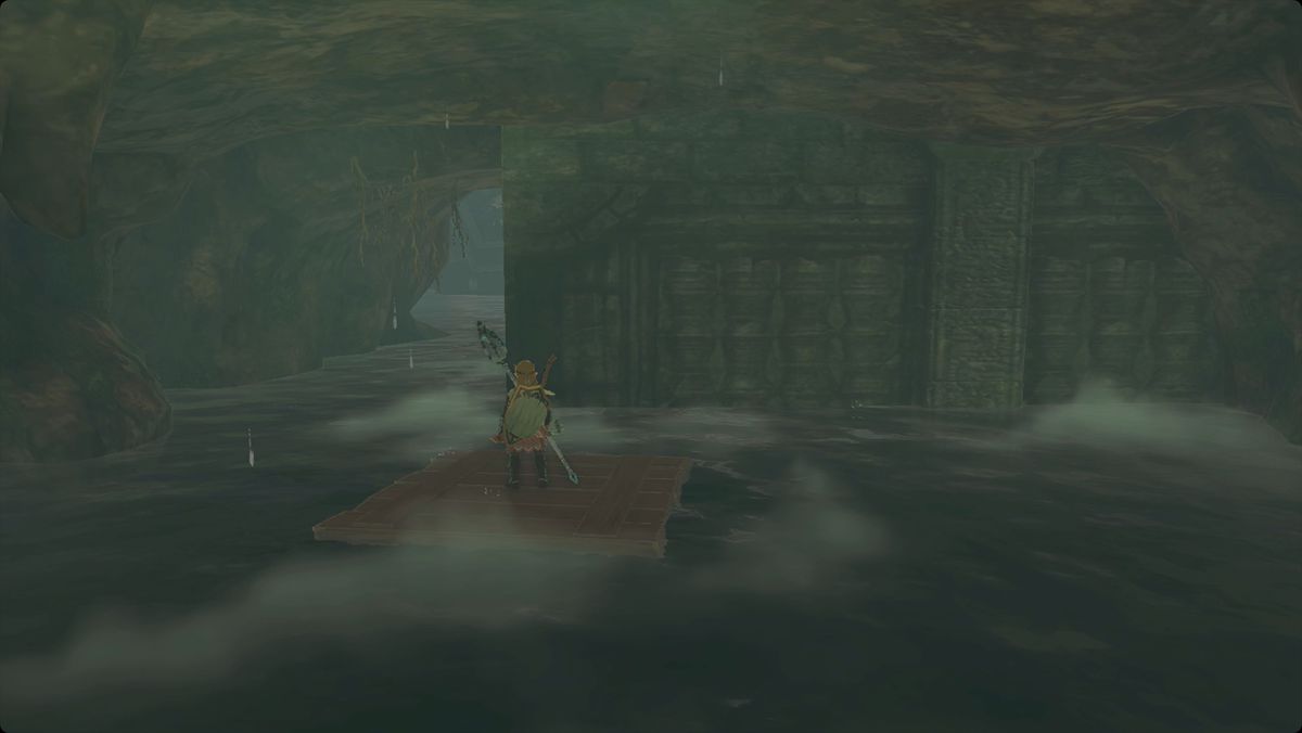 The Legend of Zelda: Tears of the Kingdom Link som står på en flytande träflotte i Cape Cales Cliffside Cave
