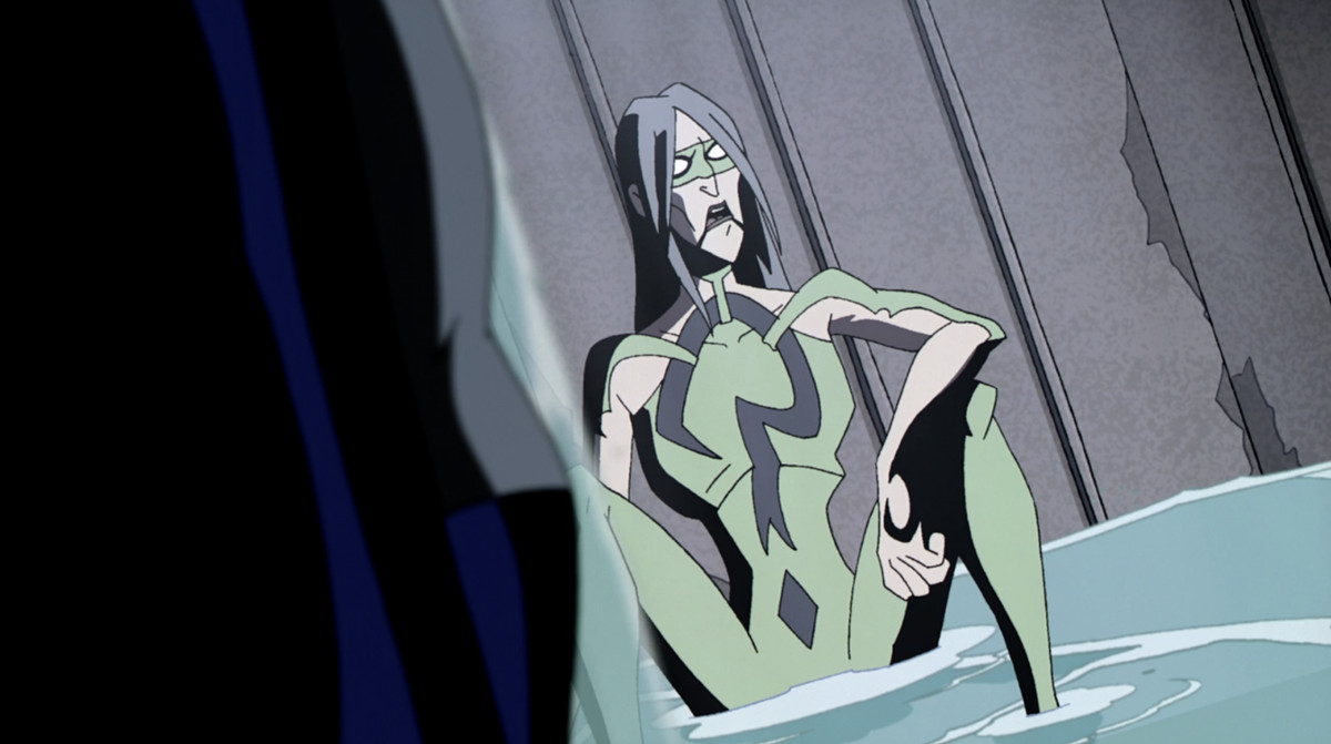 The Riddler, sittande på marken iförd en hudtät grön kostym med ett frågetecken och en mask