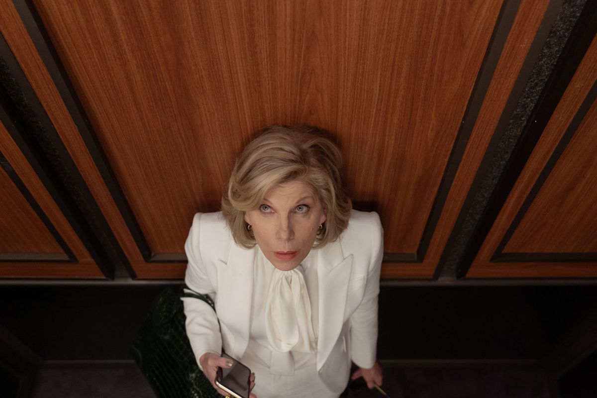 Diane Lockhart, a lawyer dressed in all white, holds her phone in her hand as her purse slips down to her elbow and she looks upward with an ominous expression in the Paramount Plus series The Good Fight.
