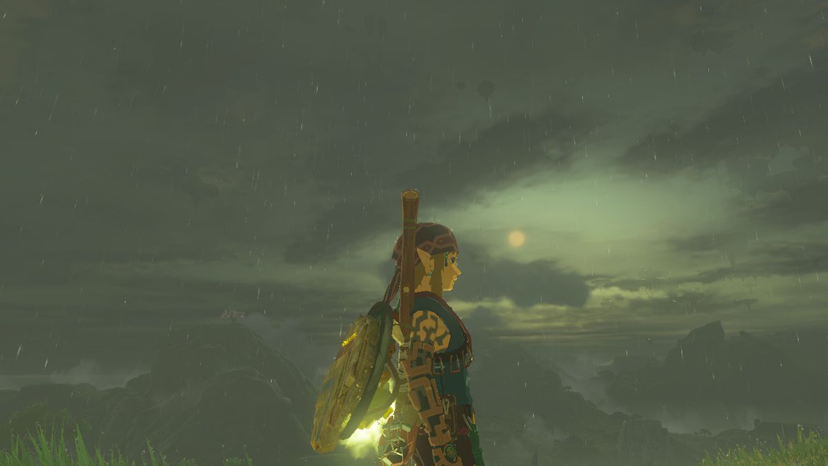 Link står på sidan under en regnig kväll med solen i fjärran iförd Climbing Armor i Zelda: Tears of the Kingdom