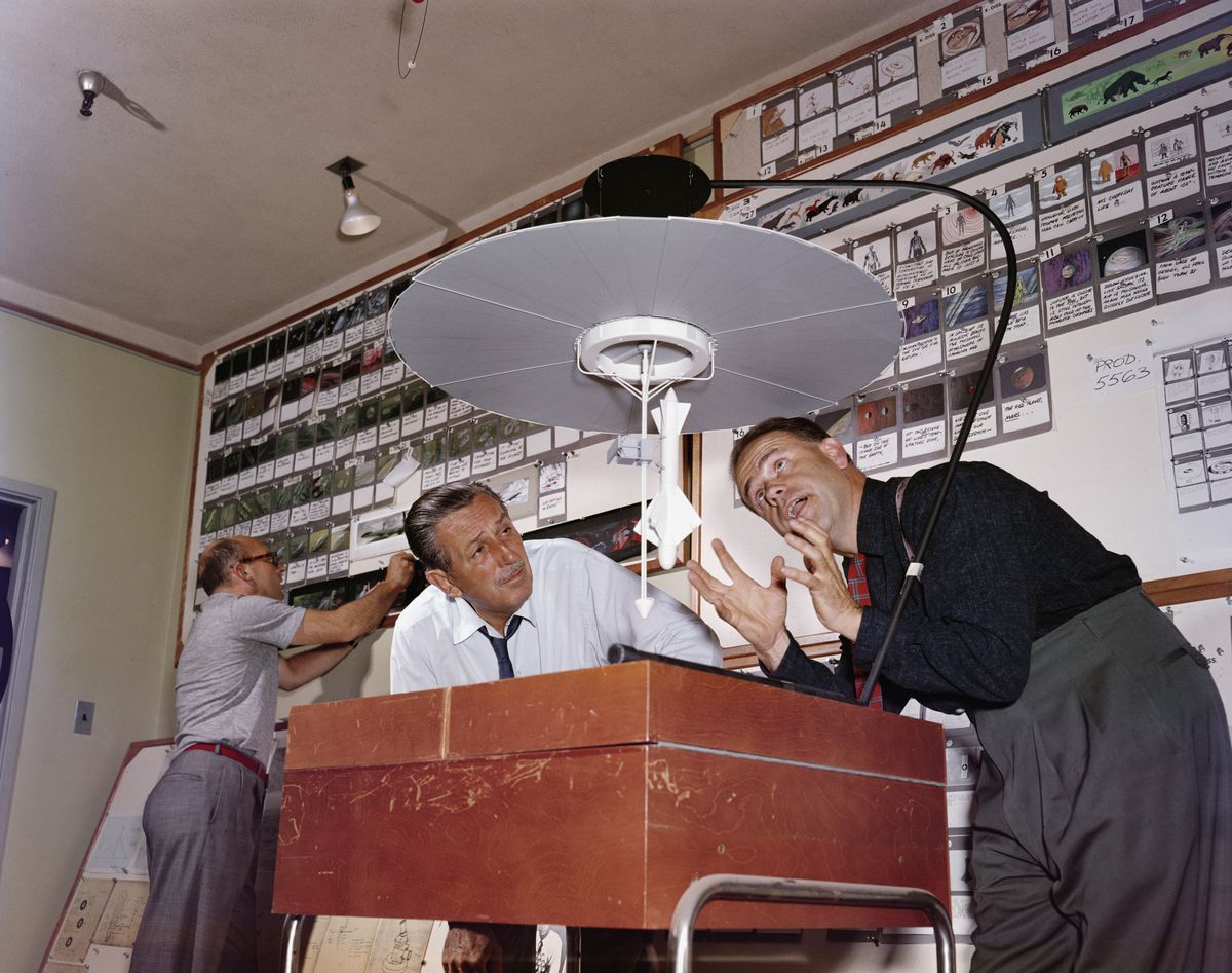Walt Disney, till vänster, står bredvid animatören Ward Kimball, med båda männen böjda över en ljuslåda under en bred rund lampa, framför en vägg täckt av storyboards för en serie från 1950-talet som heter Tomorrowland
