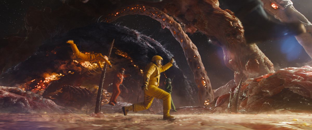 Mantis (Pom Klementieff), Drax (Dave Bautista), Peter Quill/Star-Lord (Chris Pratt) och Nebula (Karen Gillan) hoppar och kliver över ytan med låg gravitation av en enorm biologisk struktur, täckt av en köttig yta med enorma hår och ben växer ur det i Guardians of the Galaxy Vol.  3.