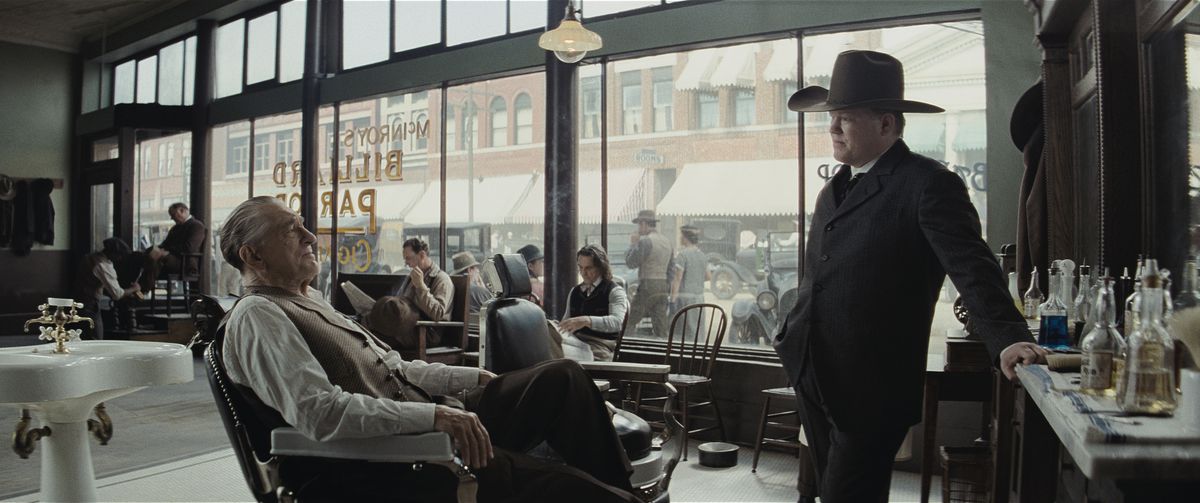 Jesse Plemons, i en enorm cowboyhatt, står och förhör Robert De Niro, sittande i en frisörsalong, i Killers of the Flower Moon