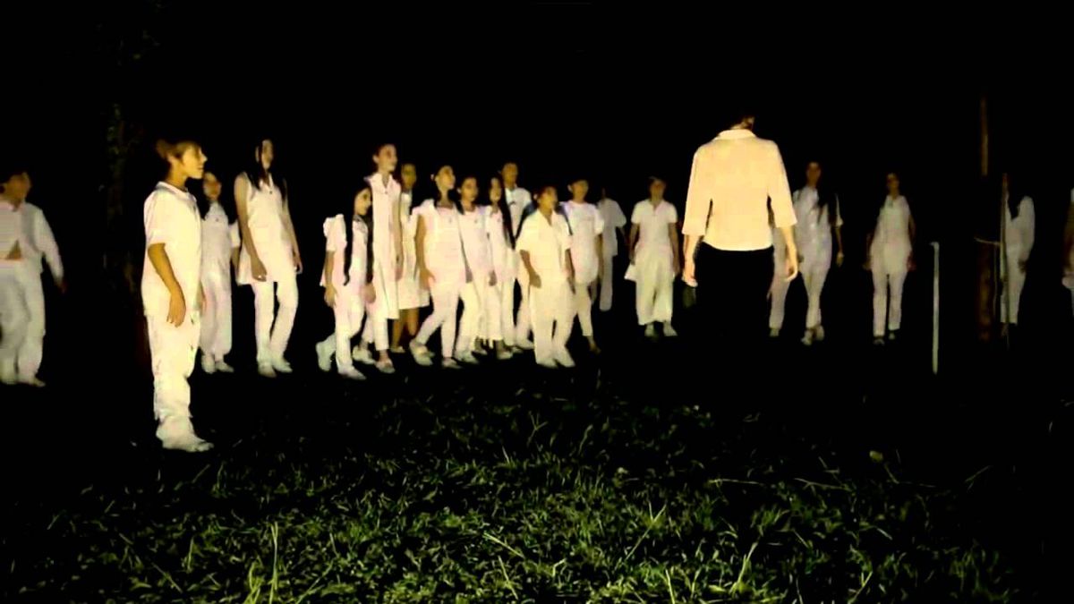 Ett gäng barn i vita kläder utför en konstig ritual på natten i gräset i Limbo (2014)