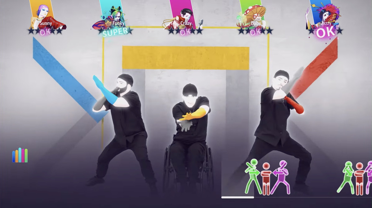 En bild av tre karaktärer i Just Dance.  Den i mitten dansar när han sitter i en rullstol.  Han sträcker sig och vrider ut sina händer i takt med låten.