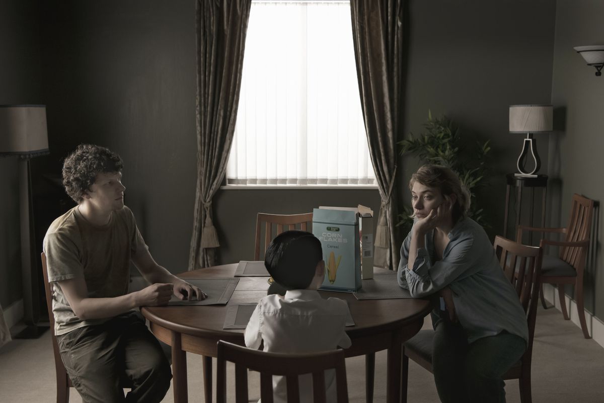 En man, kvinna och barn sitter vid ett matbord.