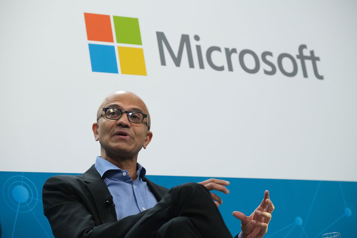 Satya Nadella, VD för Microsoft, sitter på scenen med en Microsoft-logotyp bakom sig