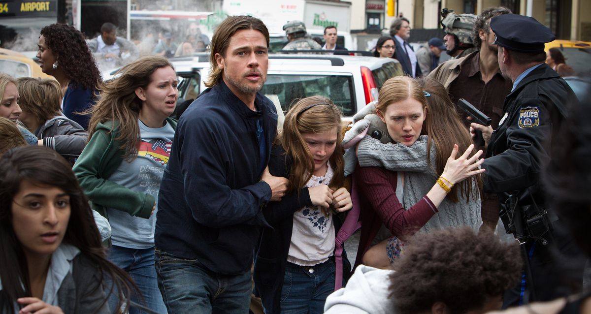I en scen från andra världskriget försöker en långhårig, orolig Brad Pitt att eskortera sin familj till säkerhet på en gata fylld med polis, panik och människor. 