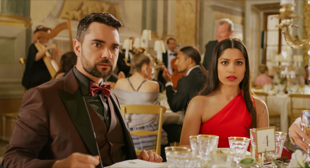 Bruttomaktparet Chaz (Allan Mustafa) och Amanda (Freida Pinto), som sitter vid ett bröllopsmottagningsbord och lyssnar vantro på något utanför skärmen.