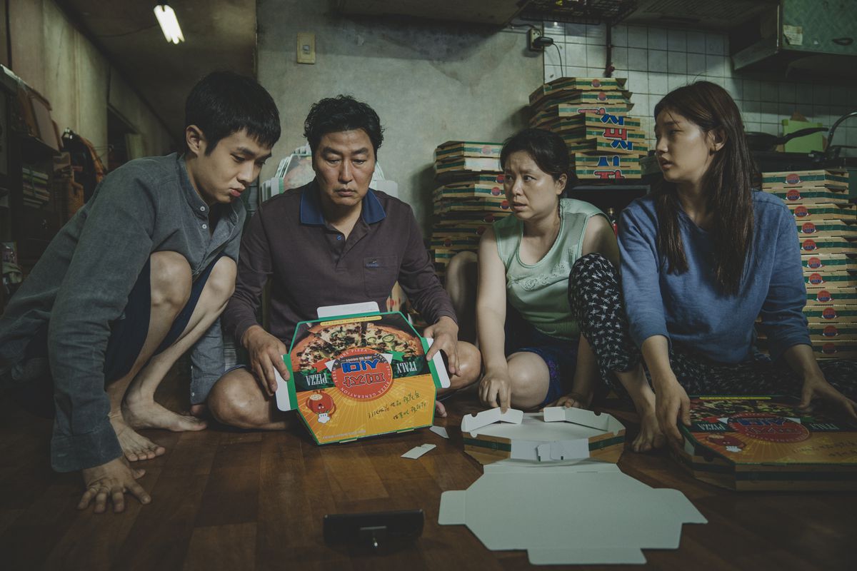 en koreansk son, pappa, mamma och dotter sitter i sin lilla lägenhet och fäll ut pizzaskar i parasiten