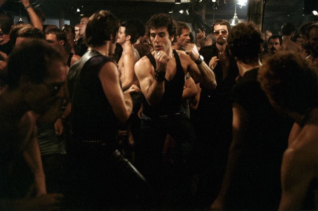 Al Pacino, i jeans och en svart ärmlös T-shirt, dansar i en mängd män i en gaybar i Cruising.