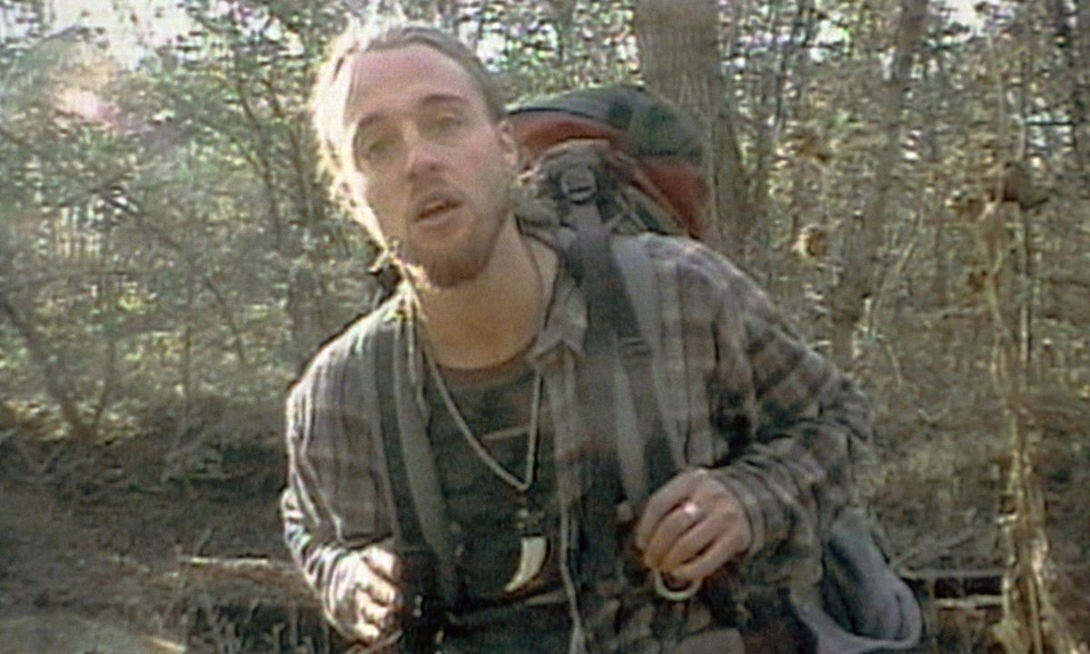 Joshua Leonard, i en grubby flanell och tung ryggsäck, står i en skog och gapar mot kameran i The Blair Witch Project.