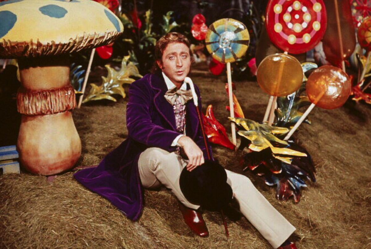 Gene Wilder som Willy Wonka, sitter bland gigantiska godisar.