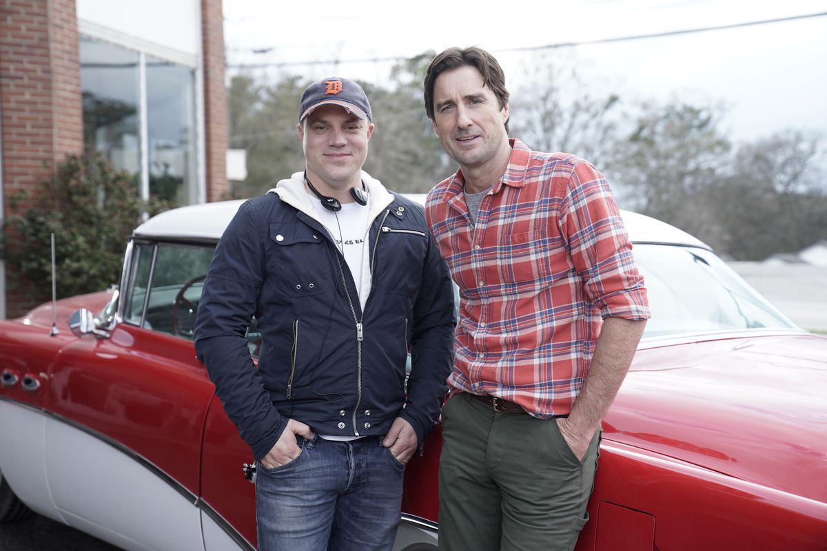 Geoff Johns och Luke Wilson i uppsättningen av Stargirl. De står framför en röd och vit restaurerad klassisk cabriolet, showens version av Star Rocket Racer.