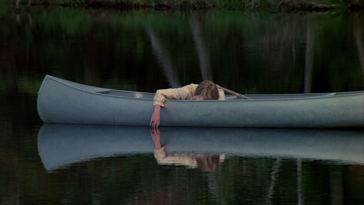 Adrienne King på fredagen den 13: e ligger i en kanot på en sjö som speglar hennes hängande arm.