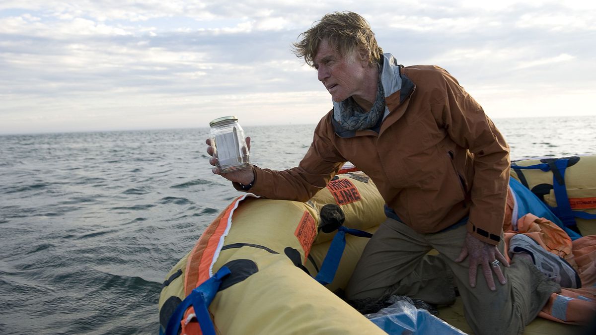 Robert Redford, ser solbränd och misshandlad när han knä i en livbåt, håller upp en burk med lite vatten i All Is Lost.