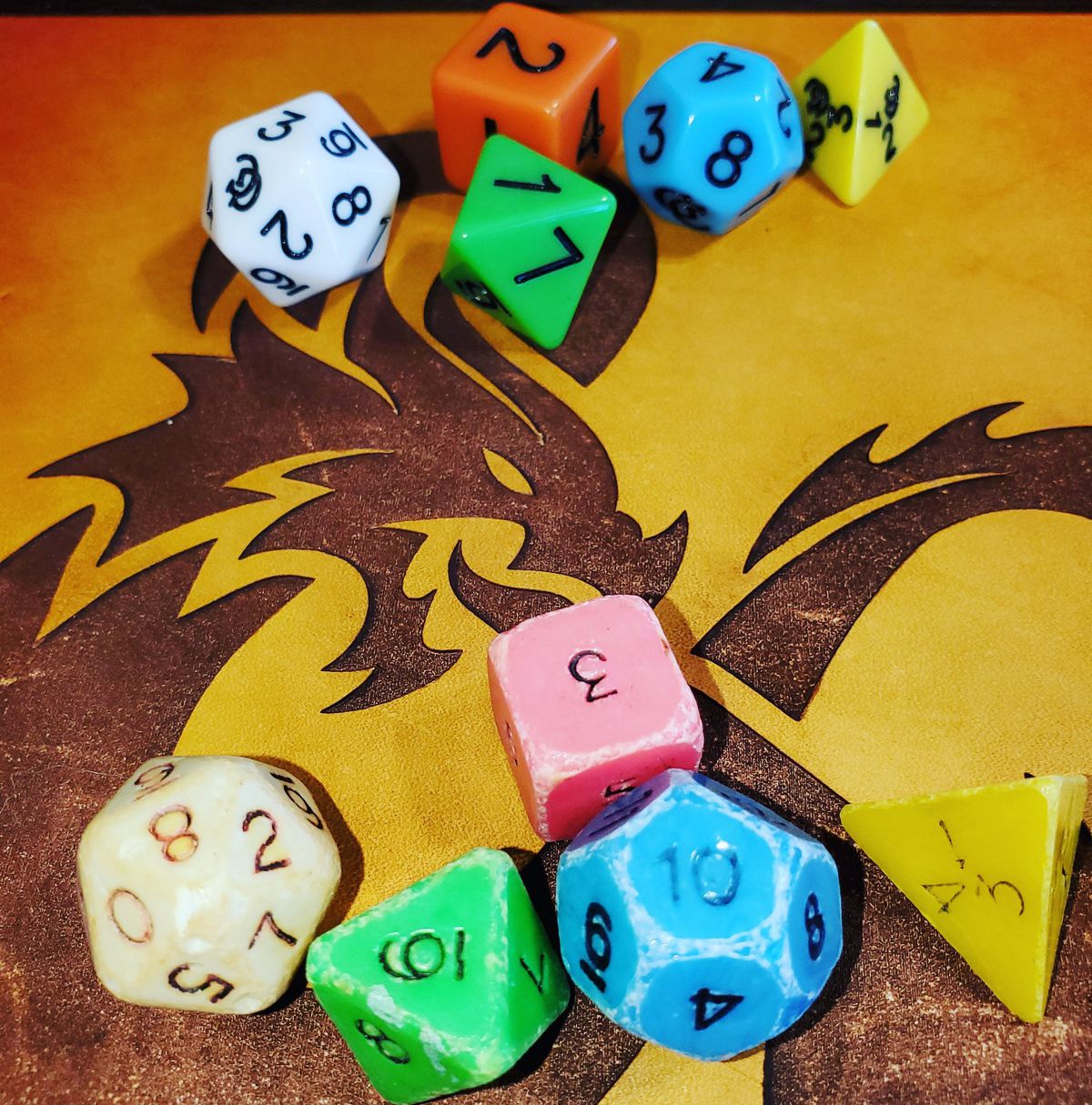 en uppsättning färgglada Dungeons & Dragons tärningar på ett bord med en drake på den