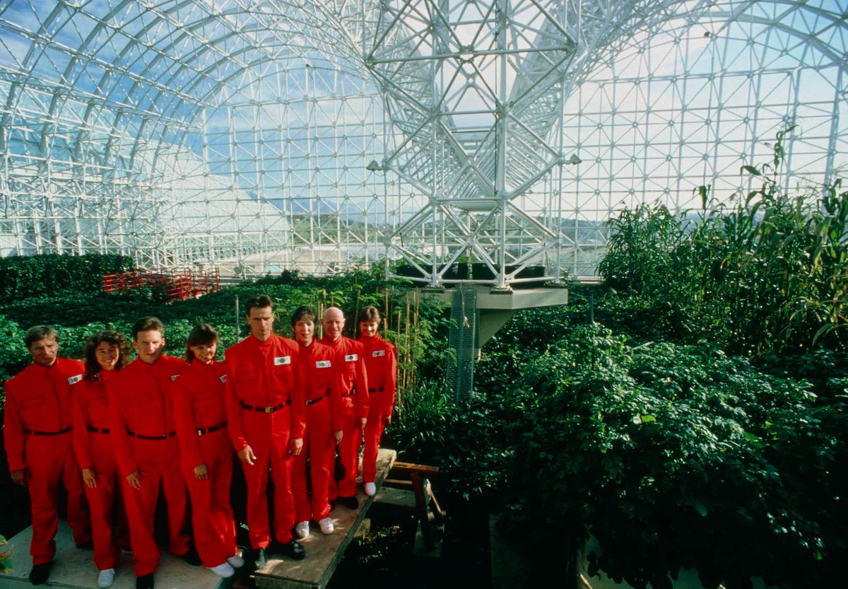 sju män och kvinnor i röda kostymer i Biosphere 2 i en stillbild från det dokumentära rymdskeppet Jorden