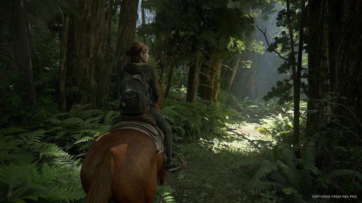 Ellie rider en häst genom en skog i en skärmdump från The Last of Us del 2