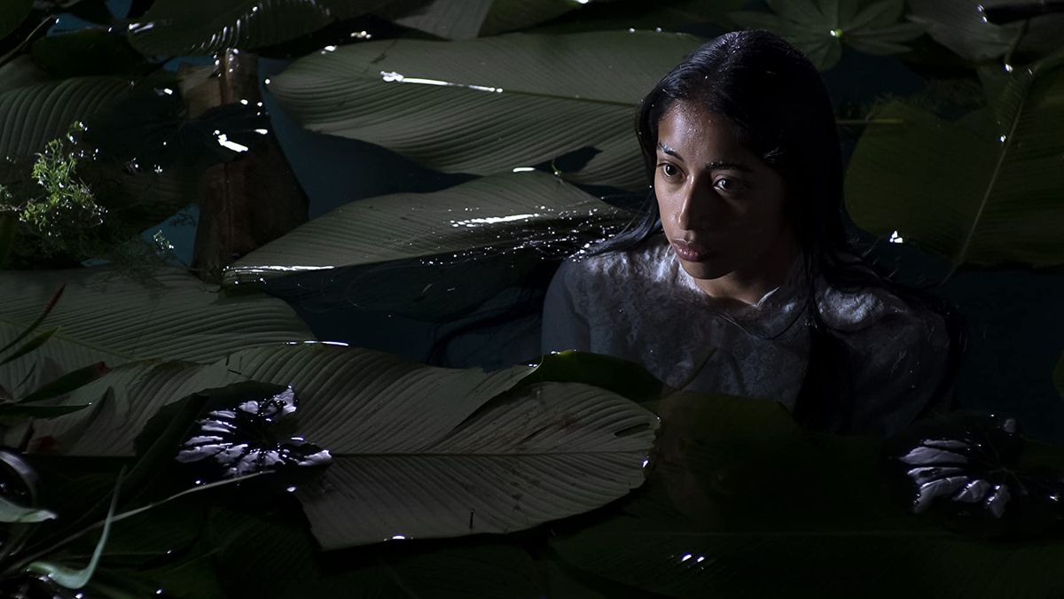 En kvinna vader i vattnet omgiven av blad