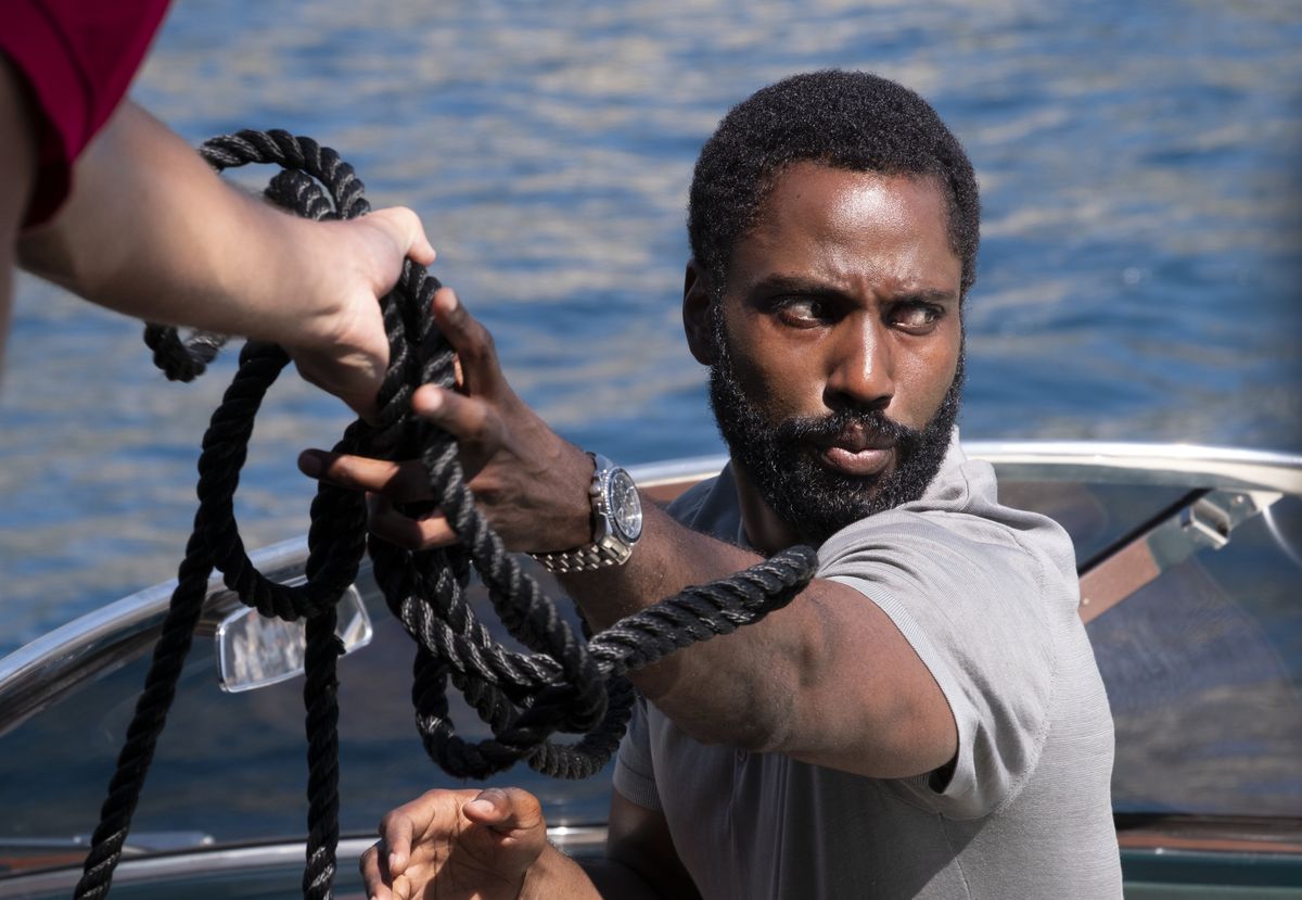 John David Washington står på en båt och tar ett tjockt svart rep i Tenet