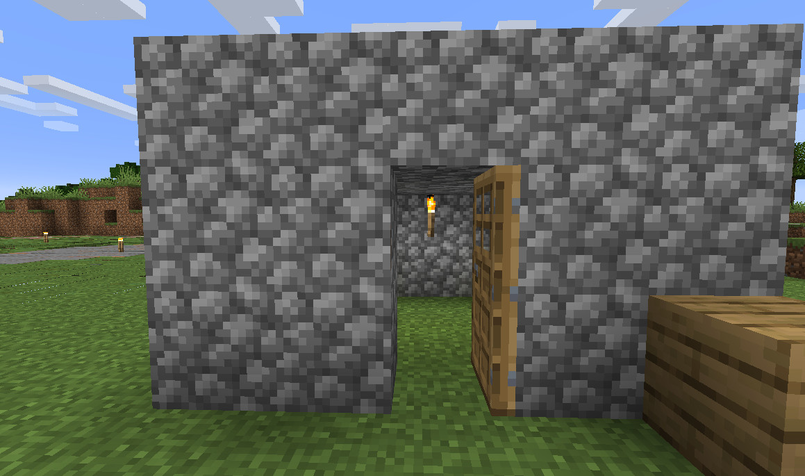 Ett litet Minecraft-hus byggt med kullersten med dörren öppen