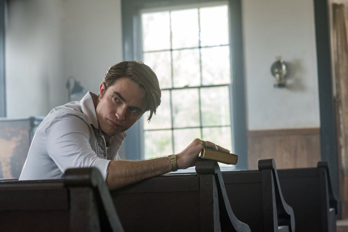 Robert Pattinson som Preston Teagardin, sitter i en kyrkobänk i The Devil All the Time