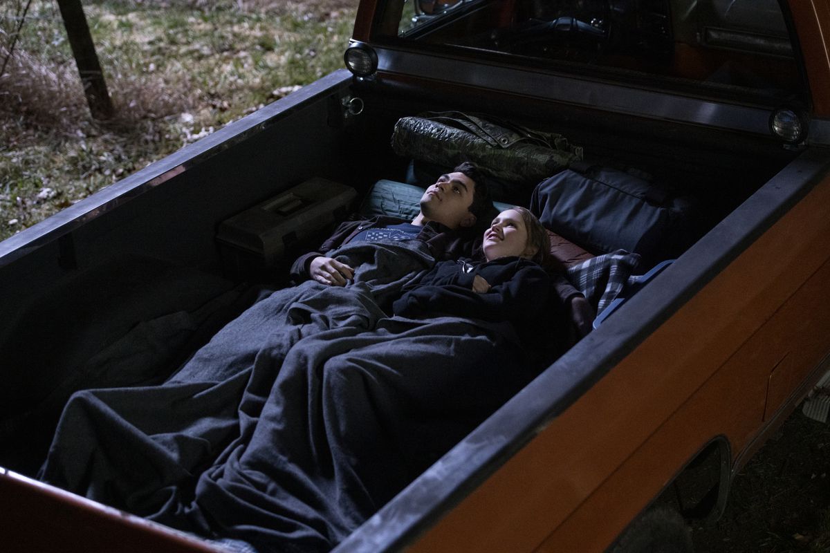 Adam Irigoyen och Talitha Eliana Bateman ligger under en filt i en lastbilsäng och tittar upp på natthimlen i Netflix-serien Away.