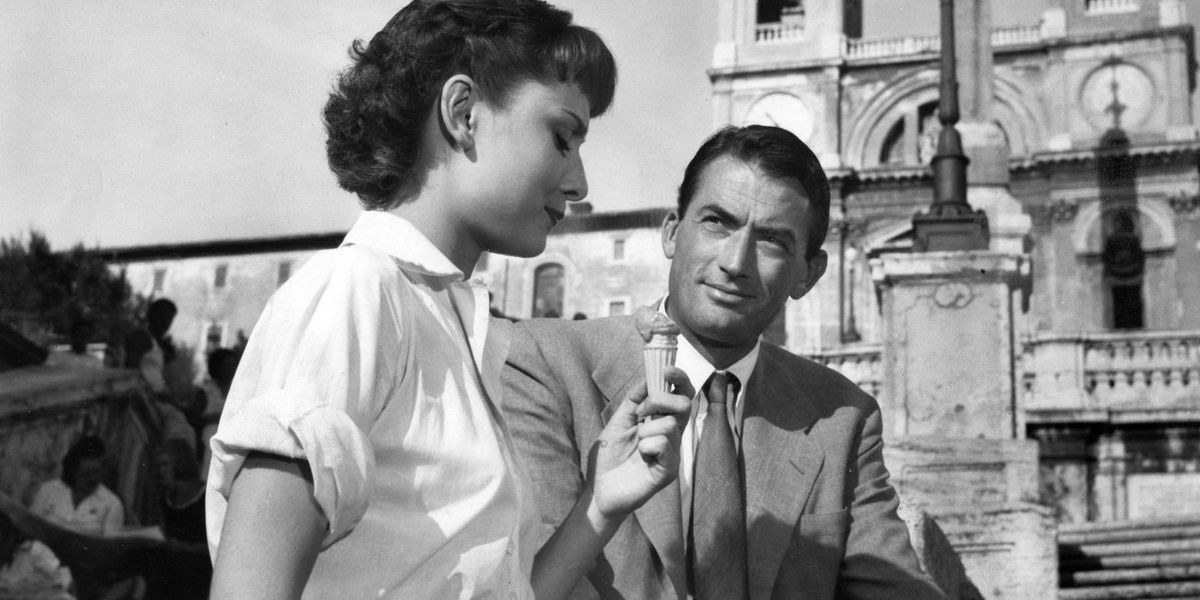 Audrey Hepburn äter en glasskotte som Gregory Peck tittar på i Roman Holiday