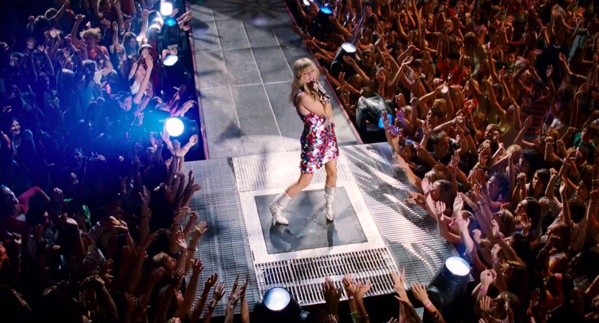 Miley Cyrus som Hannah Montana uppträder på en thrust-scen omgiven av en folkmassa i Hannah Montana