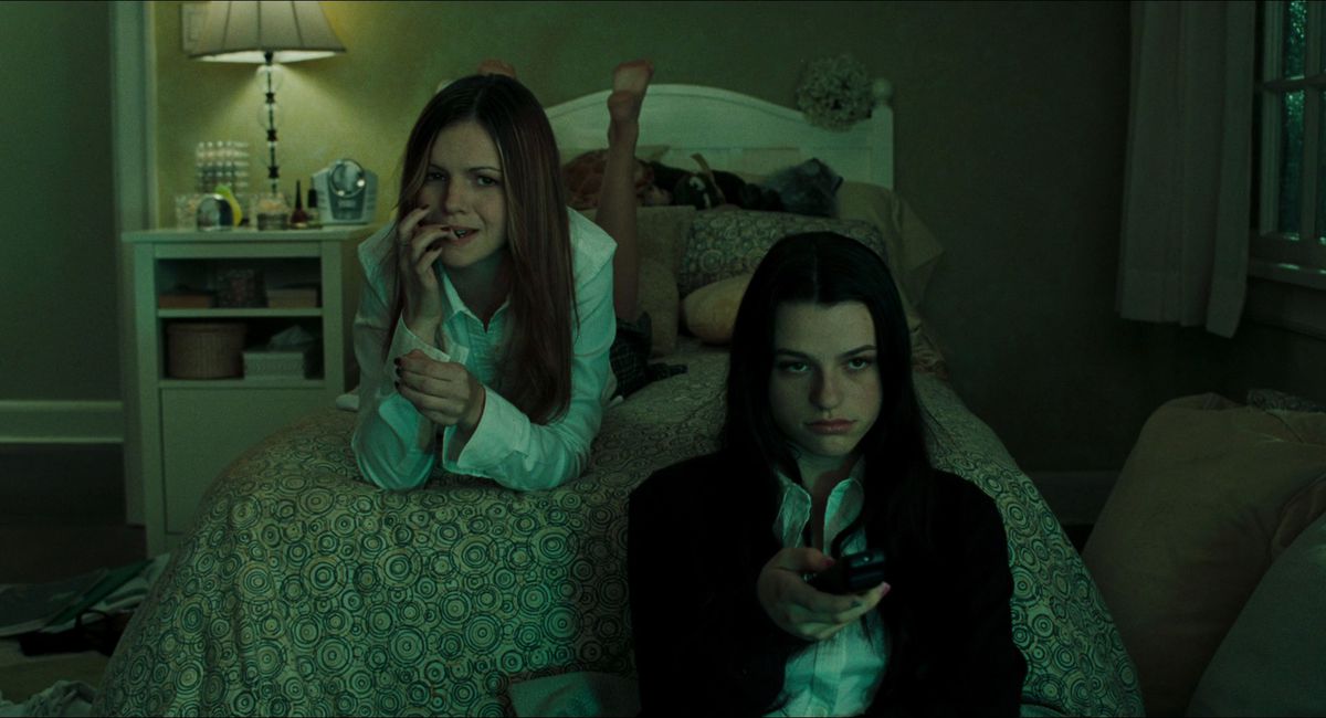 Tonåringarna Katie (Amber Tamblyn) och Becca (Rachael Bella) tittar på TV på Katies säng i en skärmdump från The Ring