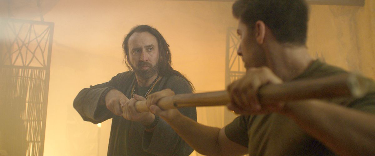 Nicolas Cage, med långt råttigt hår, vänder mot Alain Moussi när de vardera tar tag i motsatta ändar av en personal i Jiu Jitsu