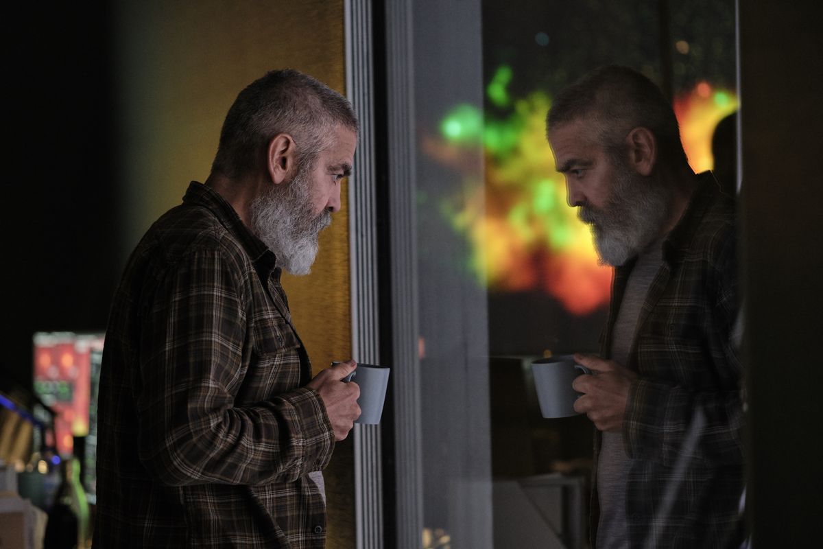 george clooney holding a cup of coffee and looking out at some spacey window in 