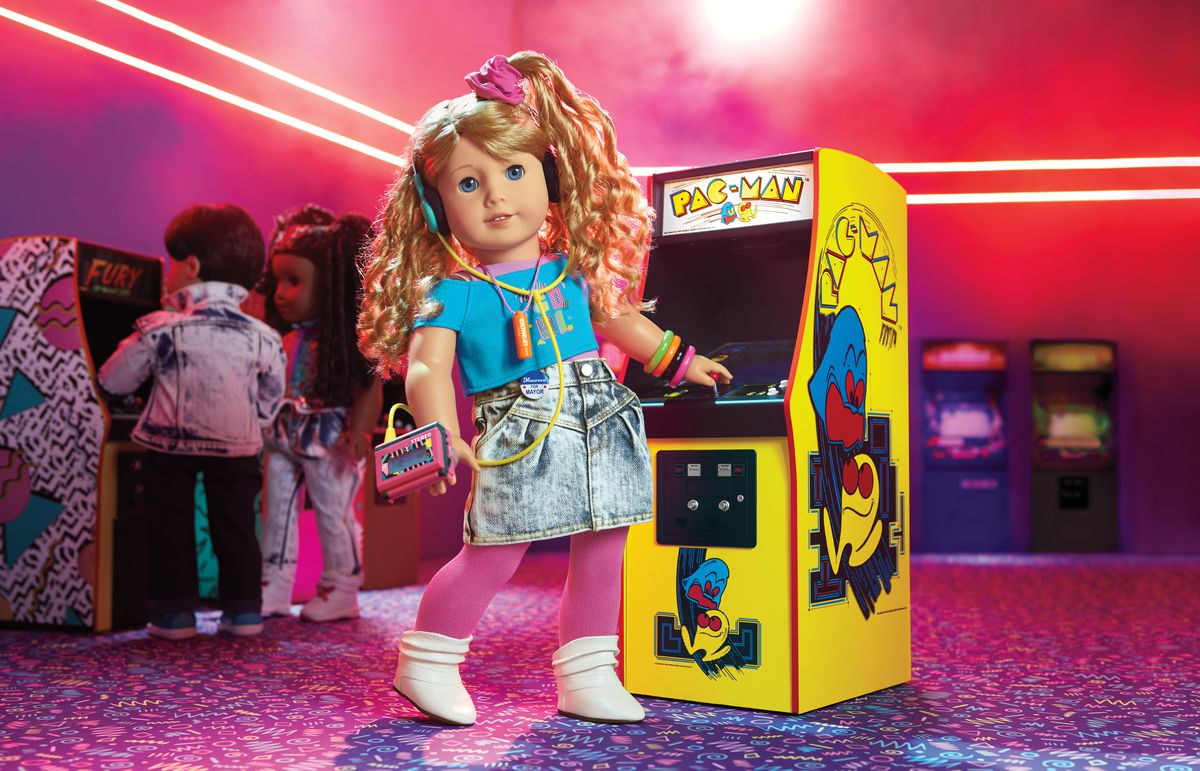 Courtney doll wears a walkman and stands in front of a Pac-Man cabinet
