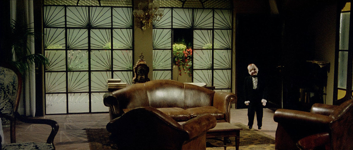 A strange mannequin stands ominously in a living room in Deep Red.