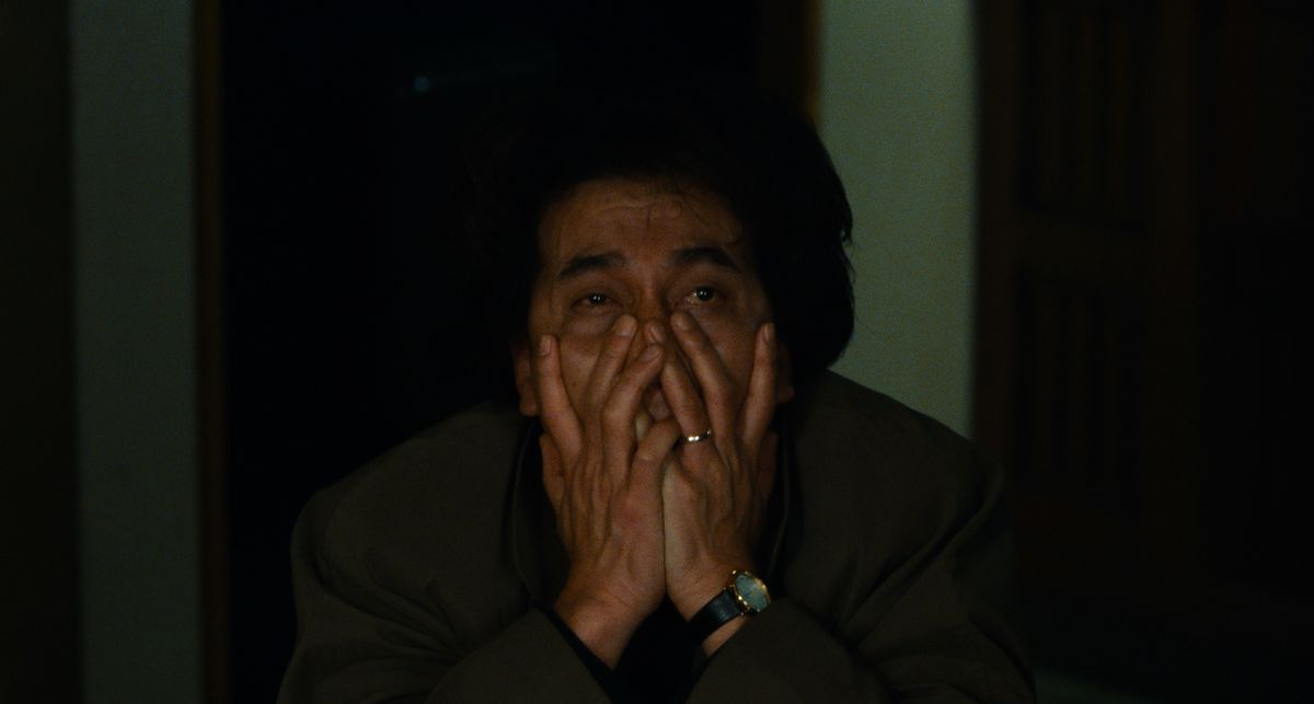 Detective Takabe (Kôji Yakusho) claspes his hands over his face in exhaustion and horror in Cure (1997)