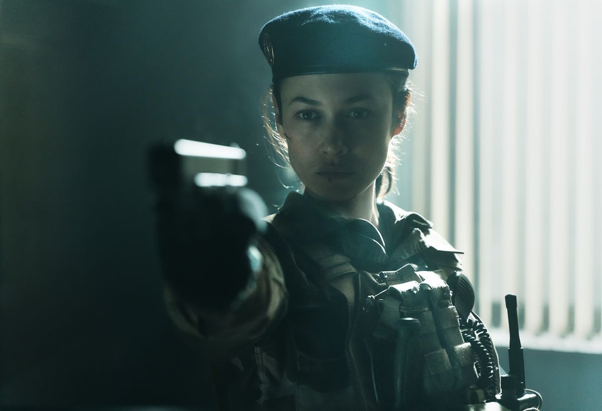 Olga Kurylenko as Klara wearing camo and beret holding a pistol in Sentinel.