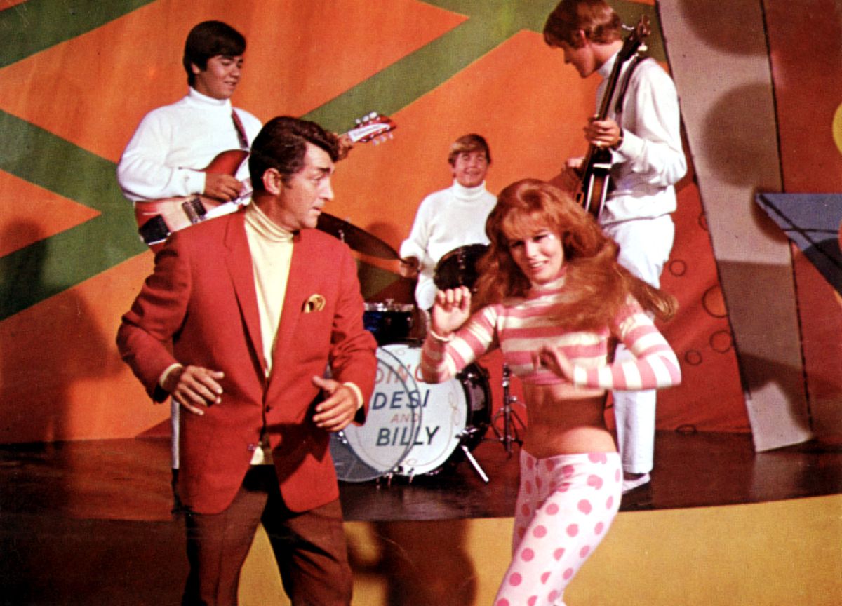 Matt Helm i röd kostym dansar med en rödhårig tjej framför bandet Desi och Billy